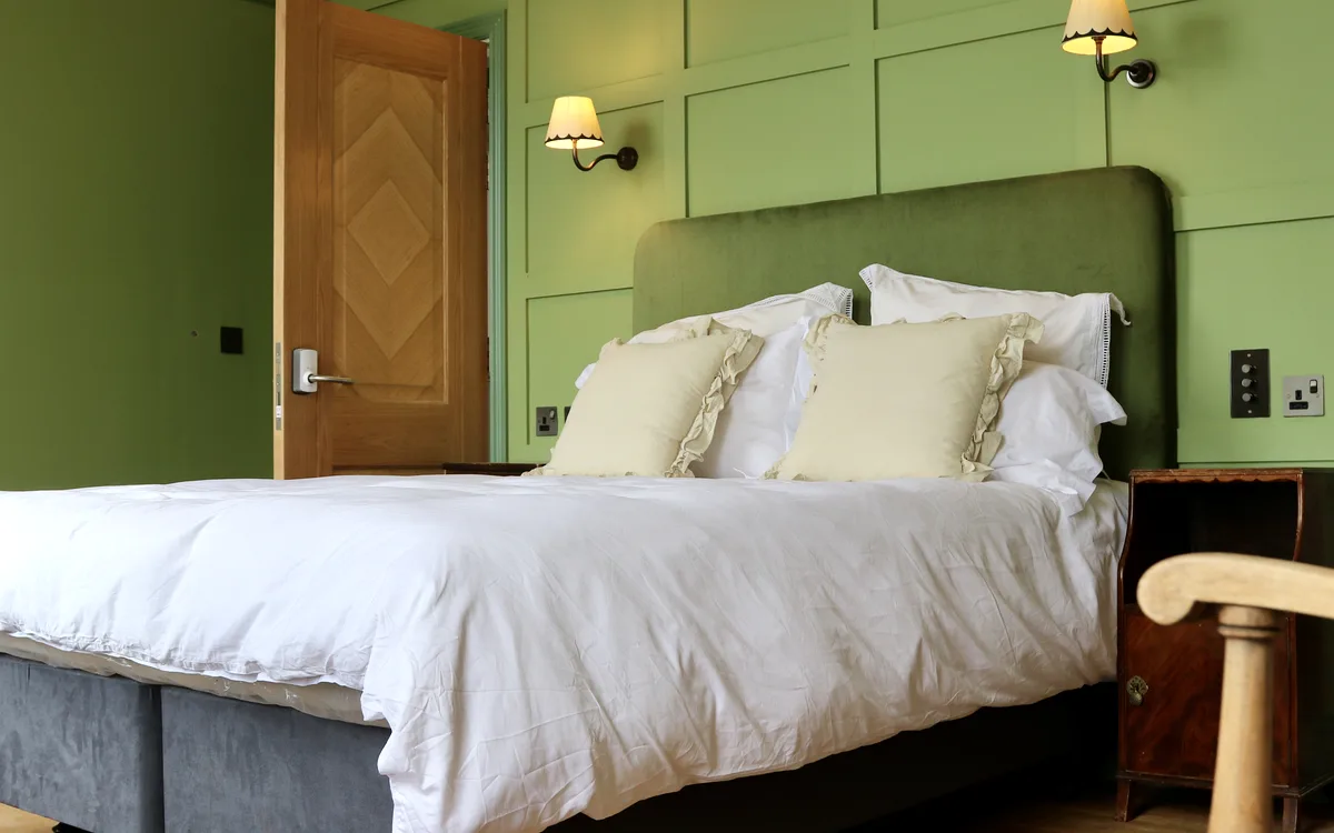 A London & Paris bedroom with a green headboard and wall lamps