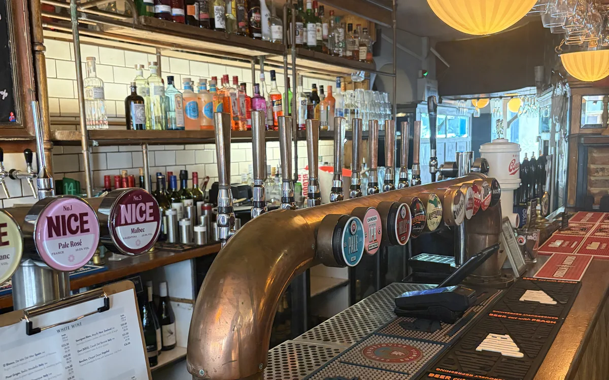 The Pullman’s bar: a copper beer font and a row of taps in front of shelves of spirits