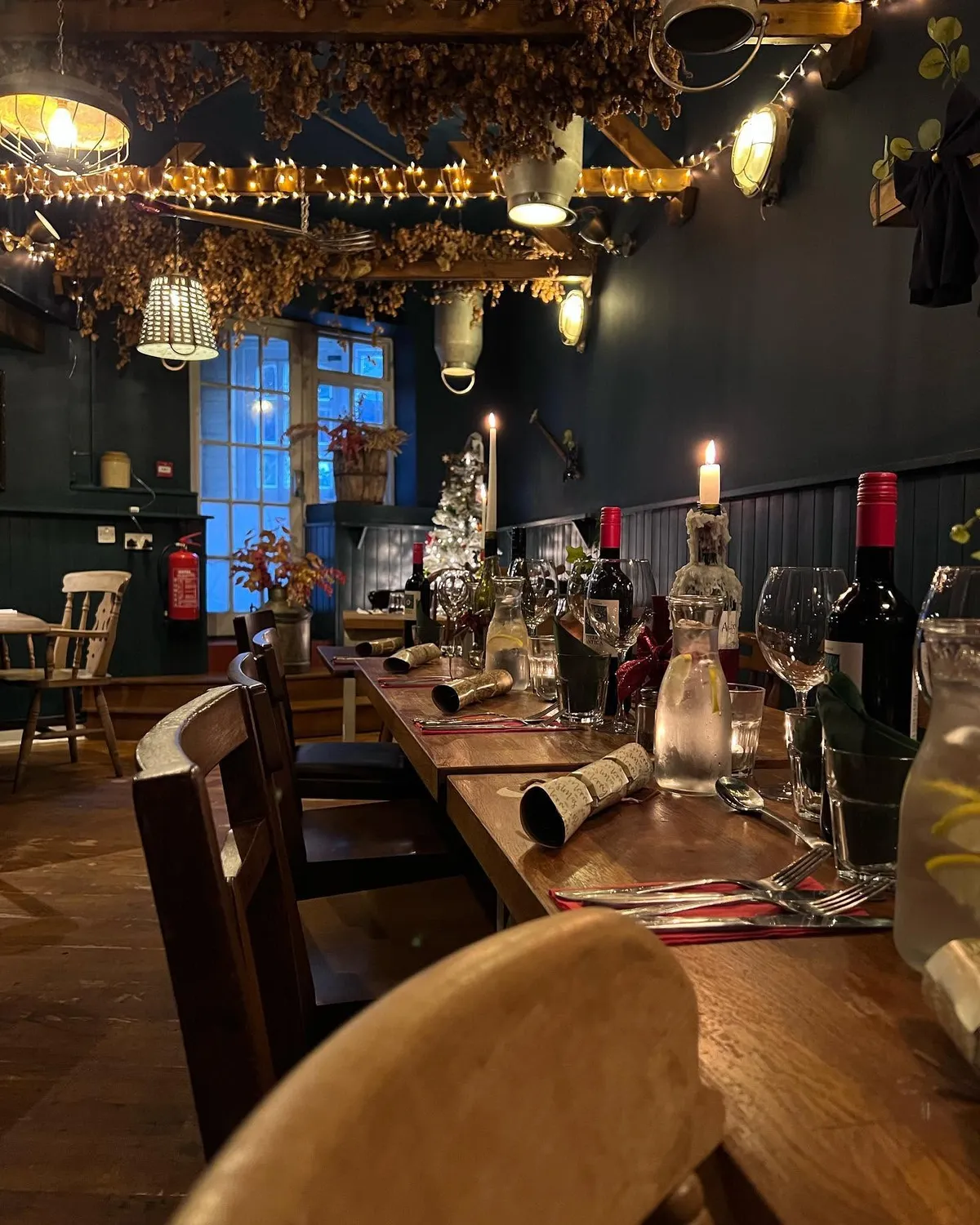 A long table set for a festive party with crackers, candles and fairy lights